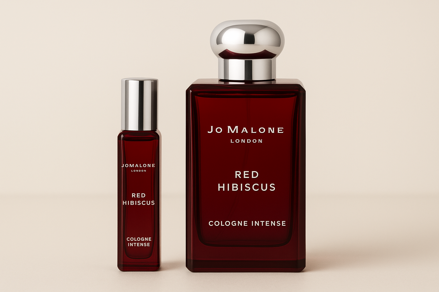 Eine 12-ml-Probe von Jo Malone Red Hibiscus Cologne Intense steht neben einer 100-ml-Parfümflasche von Jo Malone Red Hibiscus Cologne Intense, die eine weiße Schrift auf einer dunkelroten Flasche hat