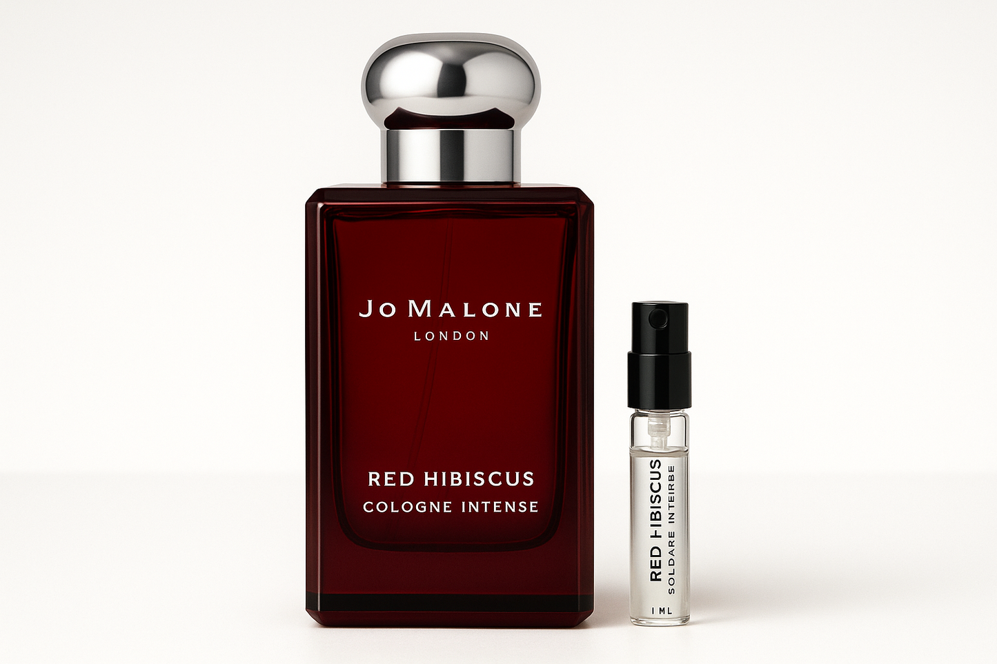 Eine 1-ml-Probe von Jo Malone Red Hibiscus Cologne Intense steht neben einer 100-ml-Parfümflasche von Jo Malone Red Hibiscus Cologne Intense, die eine weiße Schrift auf einer dunkelroten Flasche hat