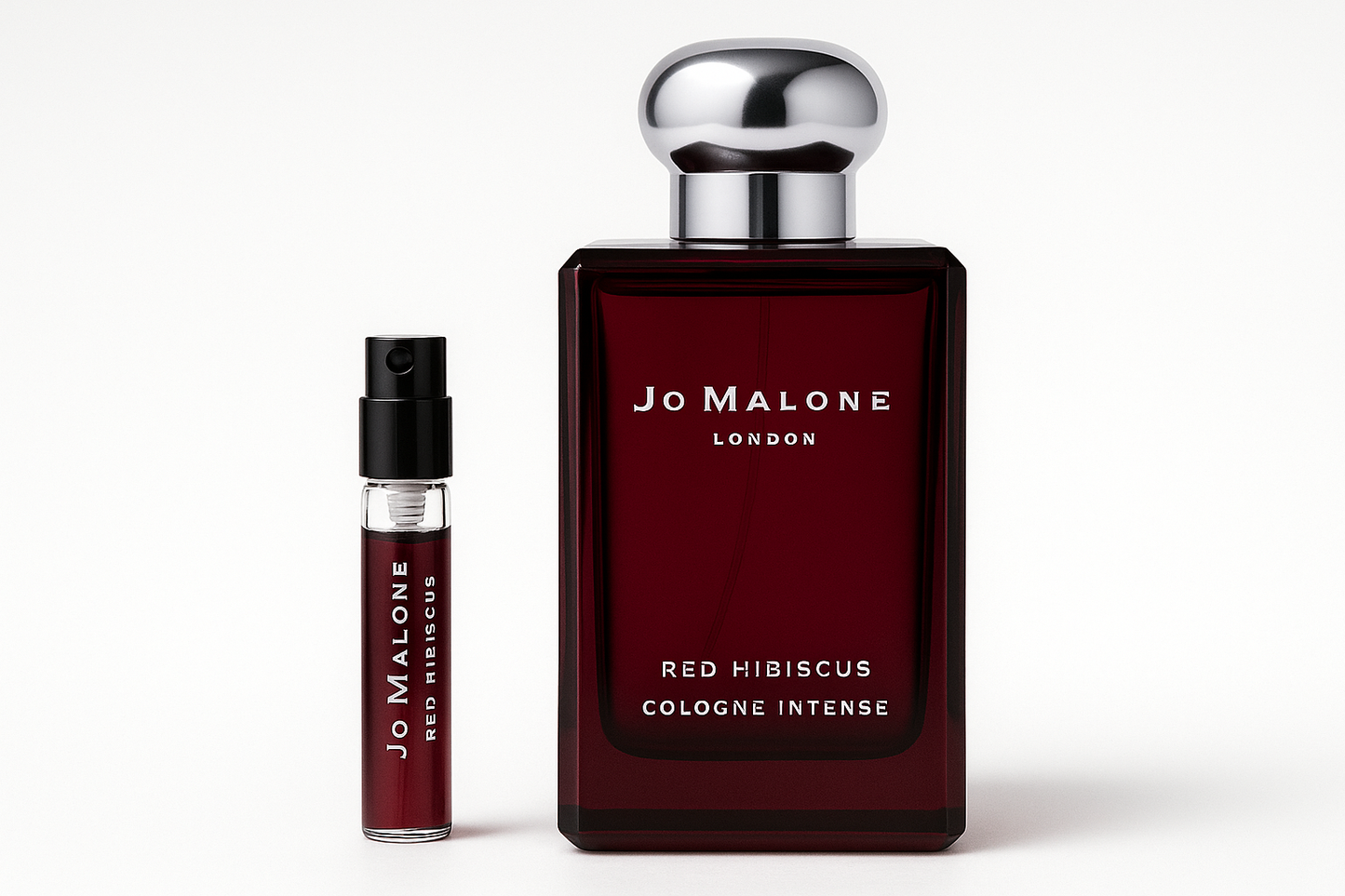 Eine 2-ml-Probe von Jo Malone Red Hibiscus Cologne Intense steht neben einer 100-ml-Parfümflasche von Jo Malone Red Hibiscus Cologne Intense, die eine weiße Schrift auf der dunkelroten Flasche hat
